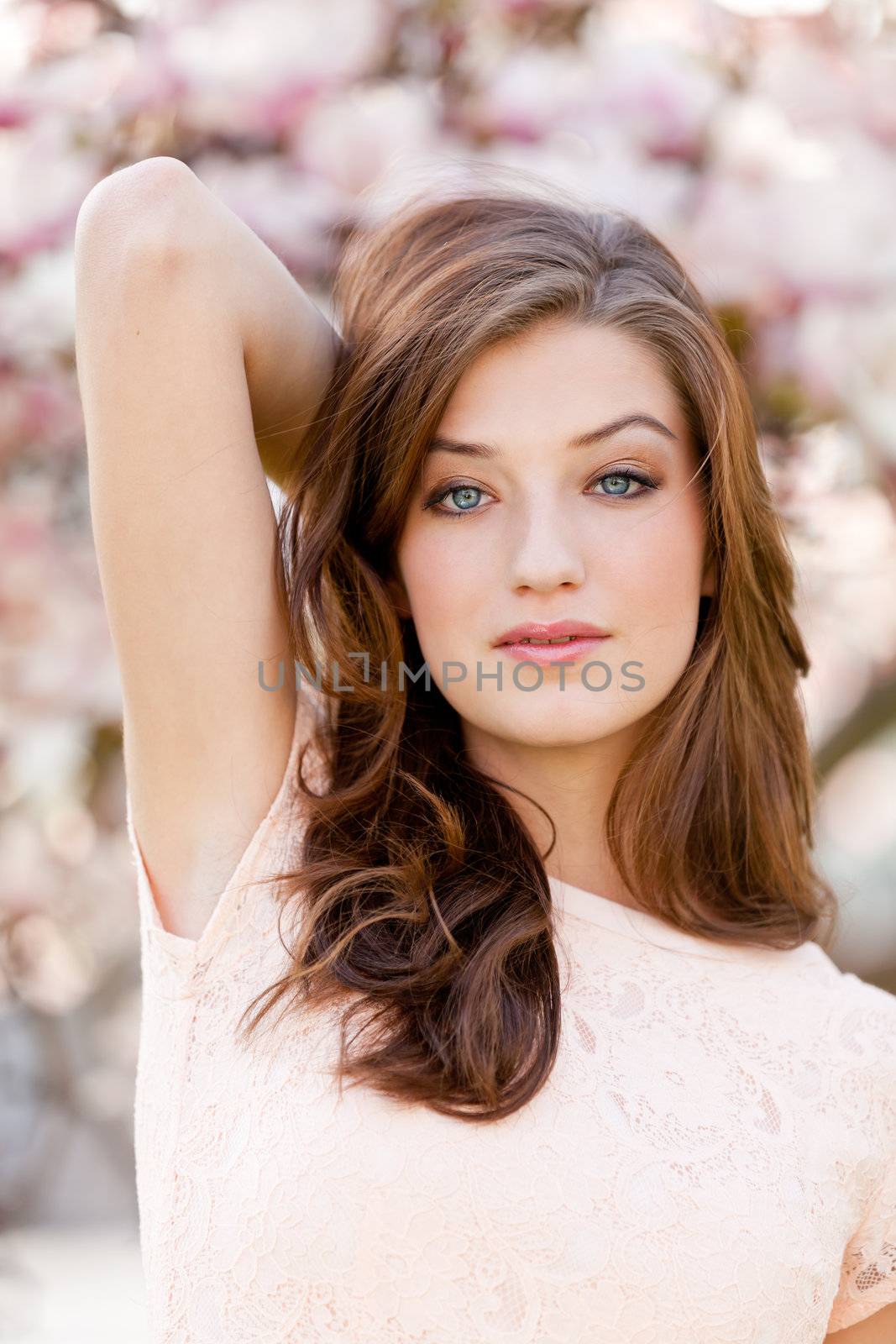 beautiful smiling woman and pink magnolia outside in spring