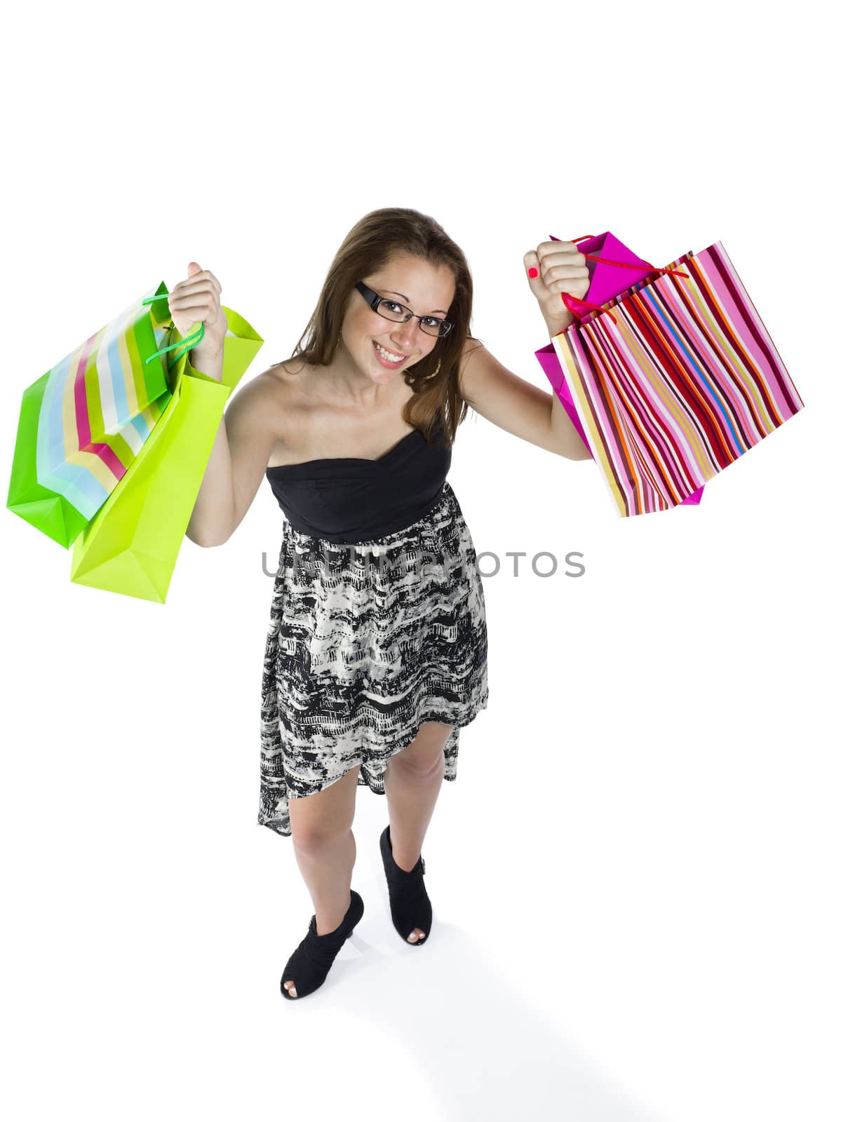 Portrait of a happy teenage girls holding up shopping bags against white background.