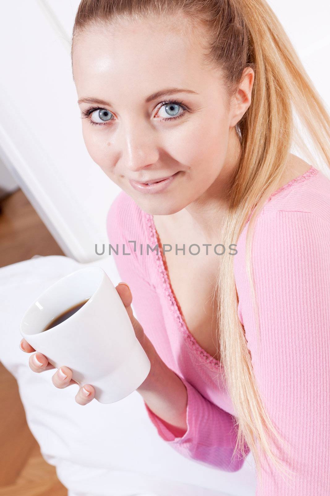 smiling young woman drinking coffee in the morning
