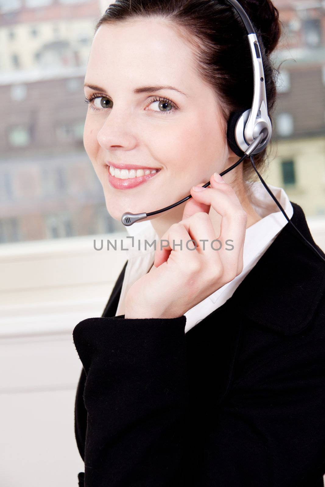 smiling young female callcenter agent with headset in office