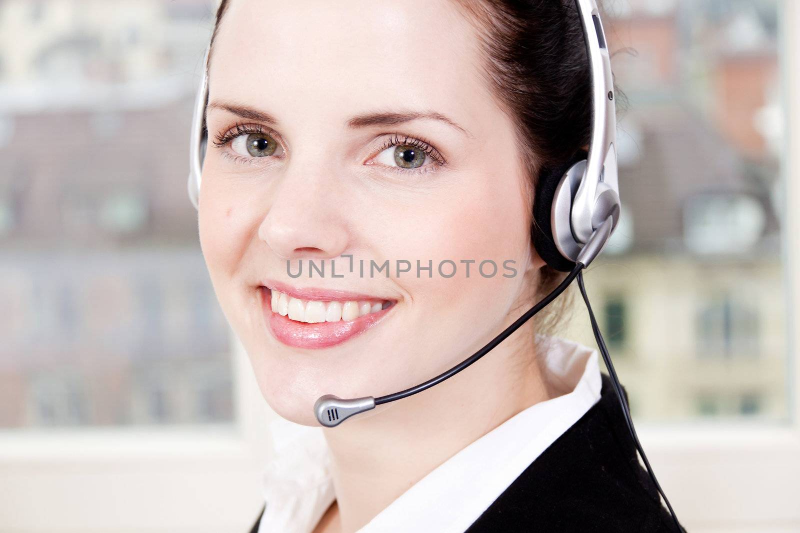 smiling young female callcenter agent with headset in office