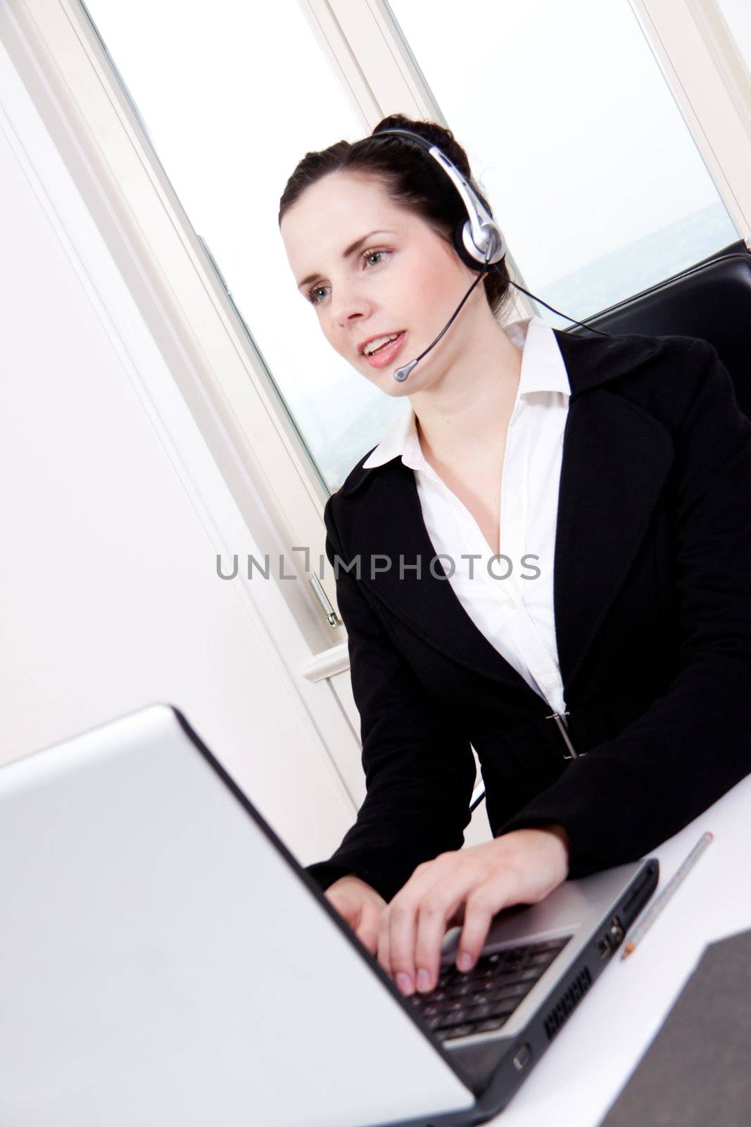 smiling young female callcenter agent with headset in office