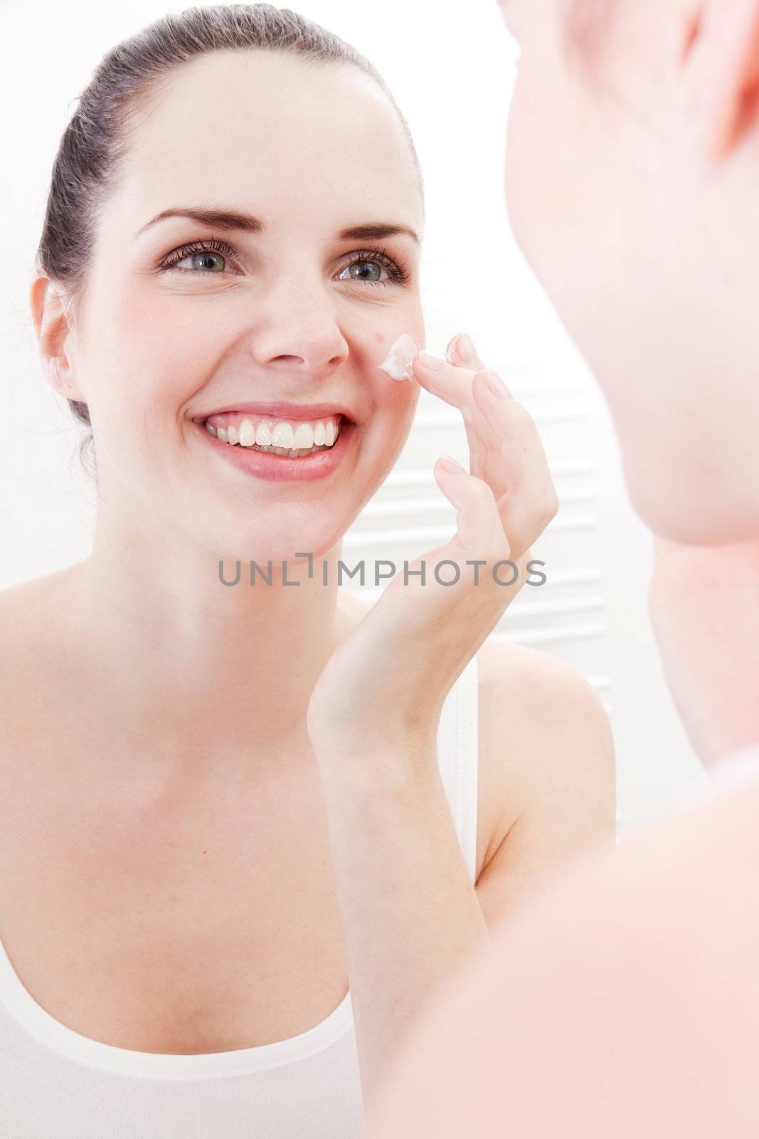 beautiful attractive woman applying cream on face skincare
