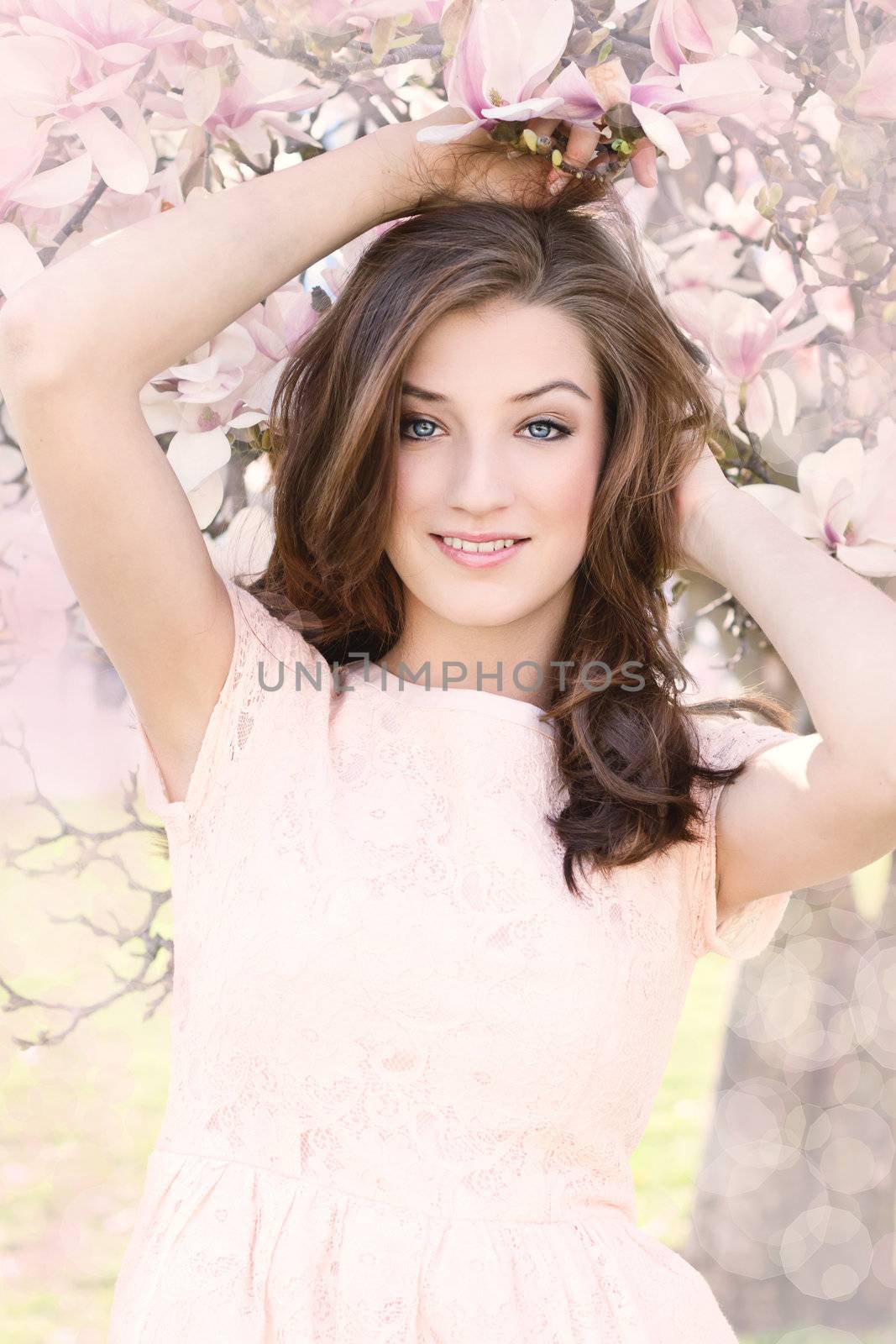 beautiful smiling woman and pink magnolia outside in spring