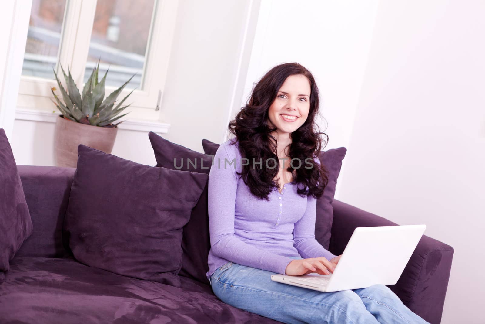 attractive young smiling woman on couch with notebook 