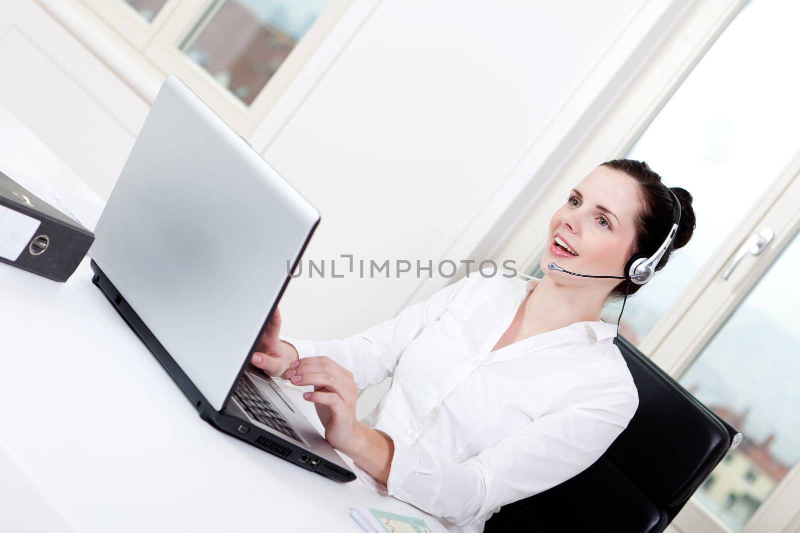 smiling young female callcenter agent with headset in office