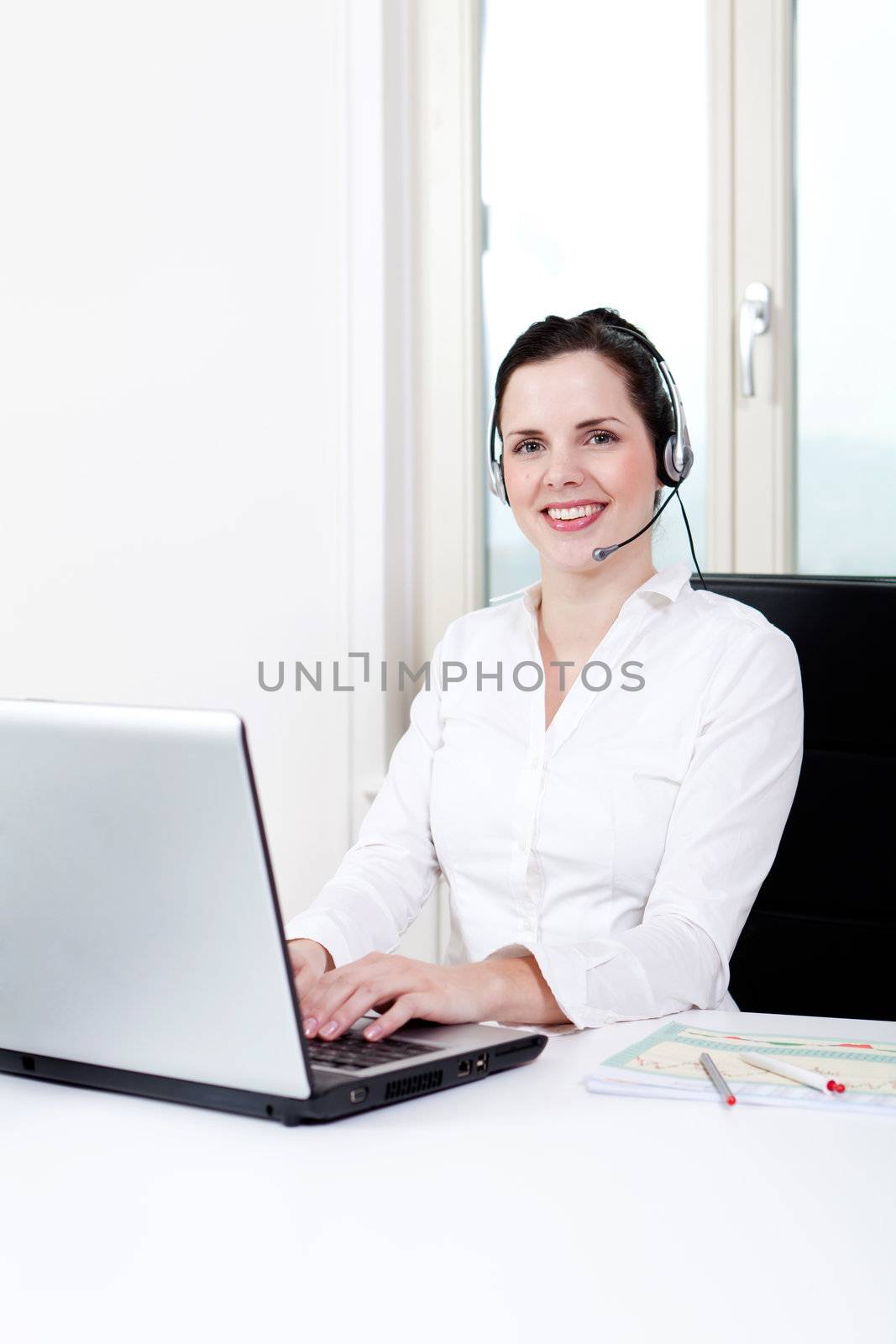 smiling young female callcenter agent with headset in office