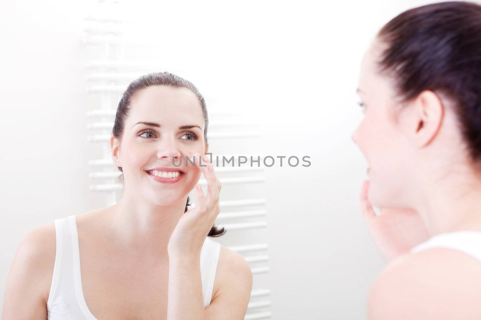 beautiful attractive woman applying cream on face skincare