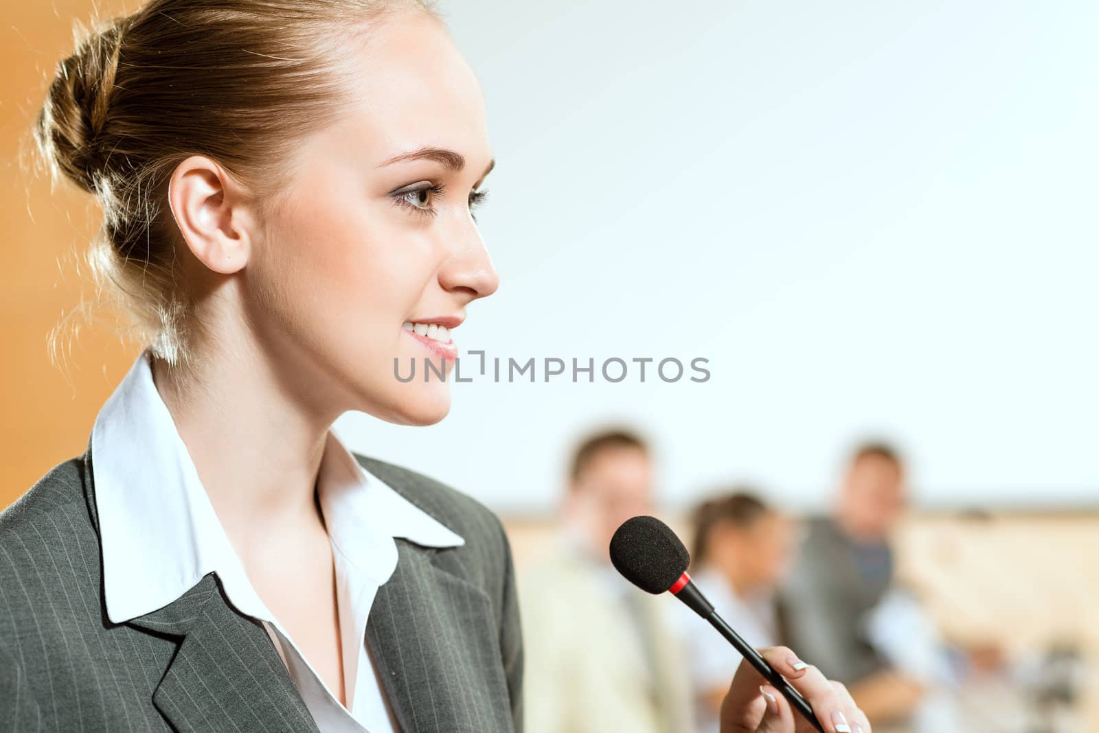 Portrait of a business woman holding a microphone and looks ahead