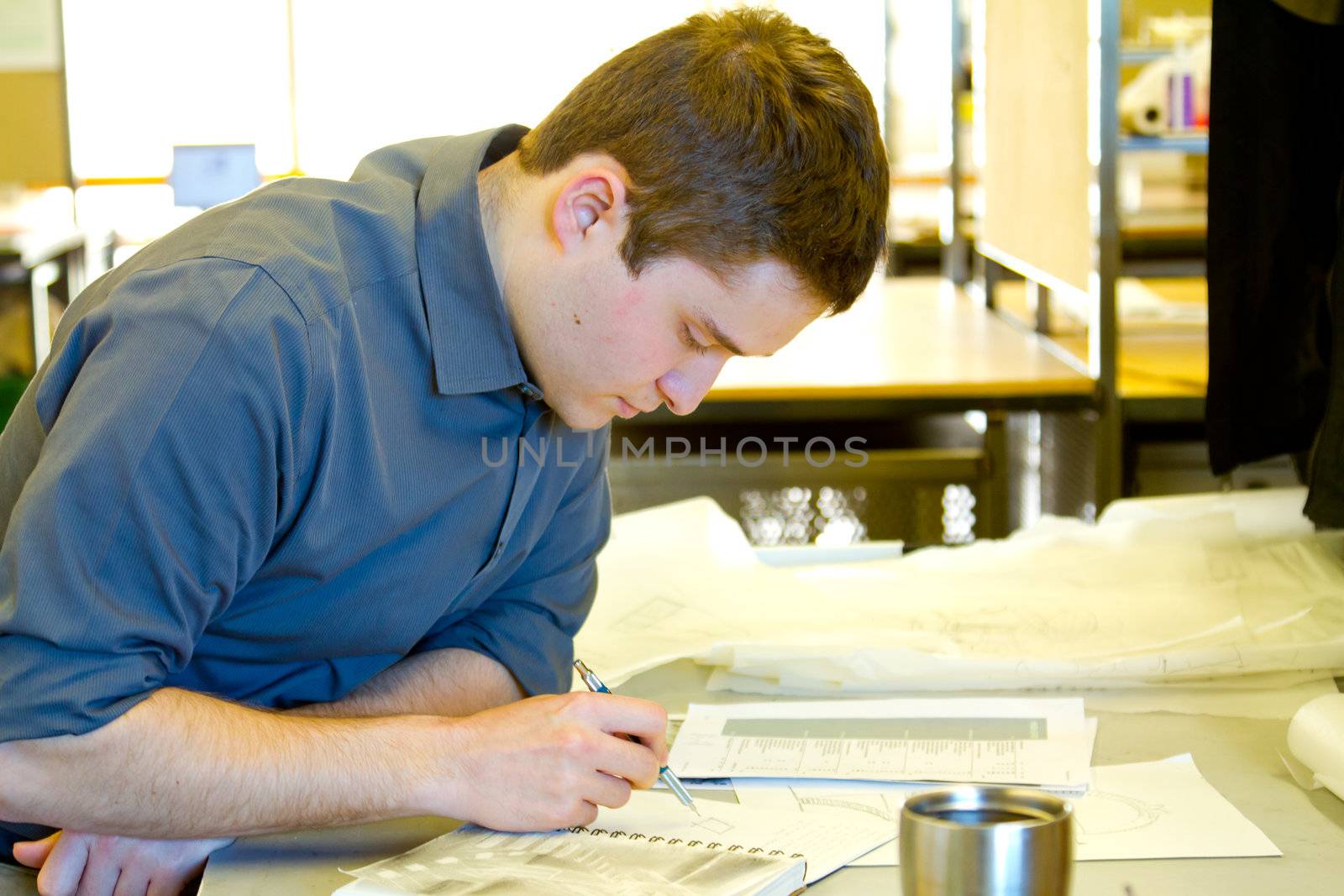 An architect studies in his college work building while drawing plans and preparing work for a class.