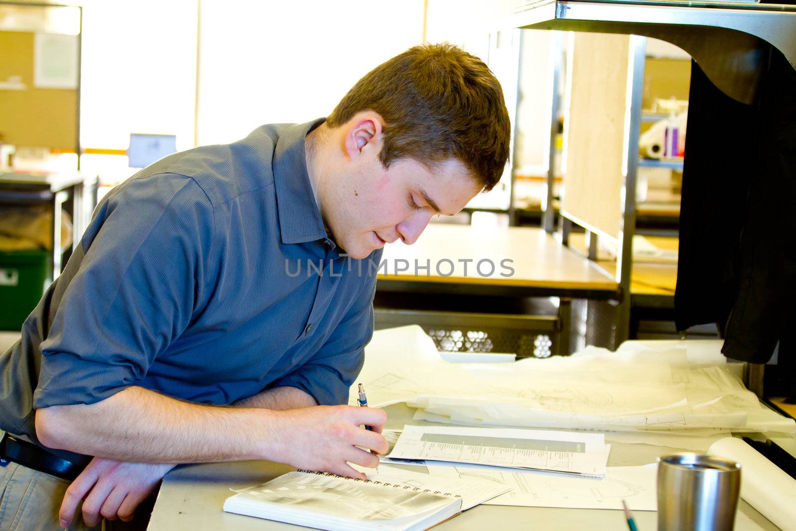 An architect studies in his college work building while drawing plans and preparing work for a class.