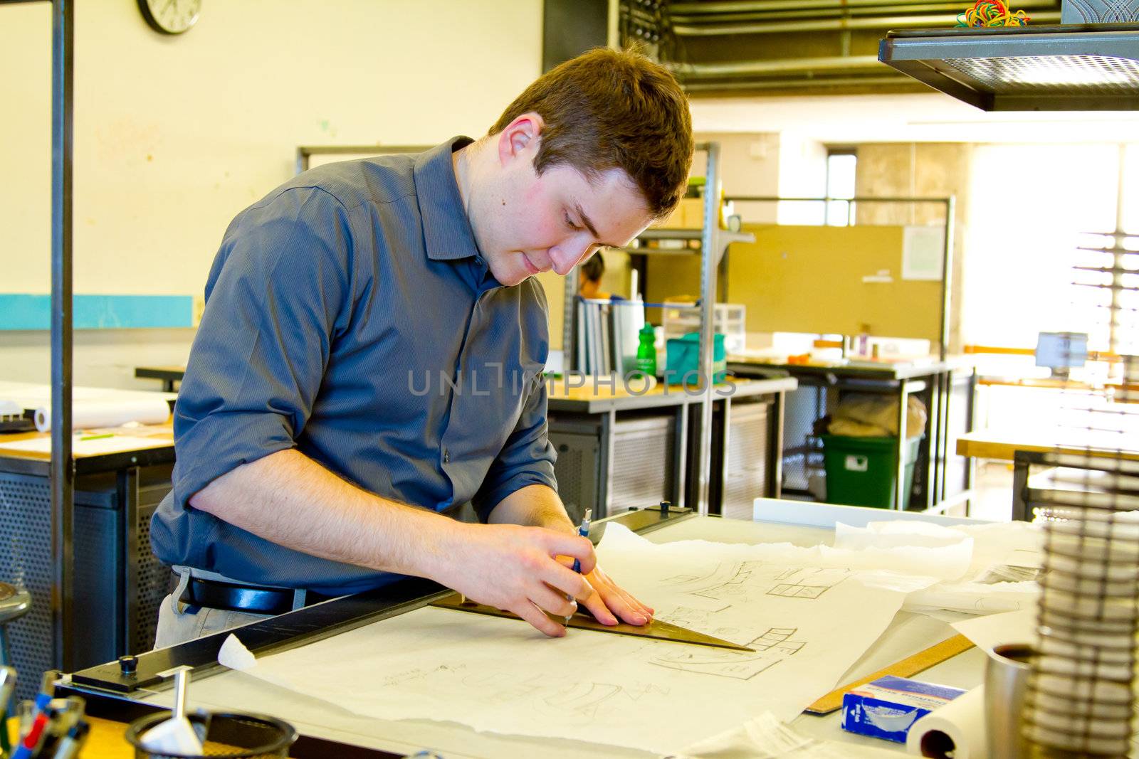 An architect studies in his college work building while drawing plans and preparing work for a class.