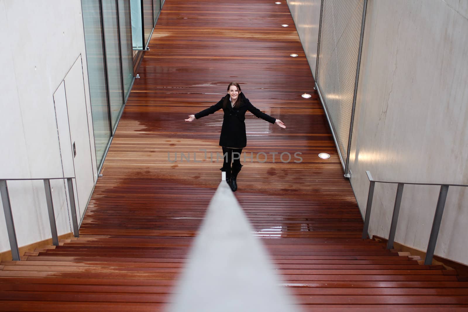 Young woman standing with hands apart on a wet wooden floor