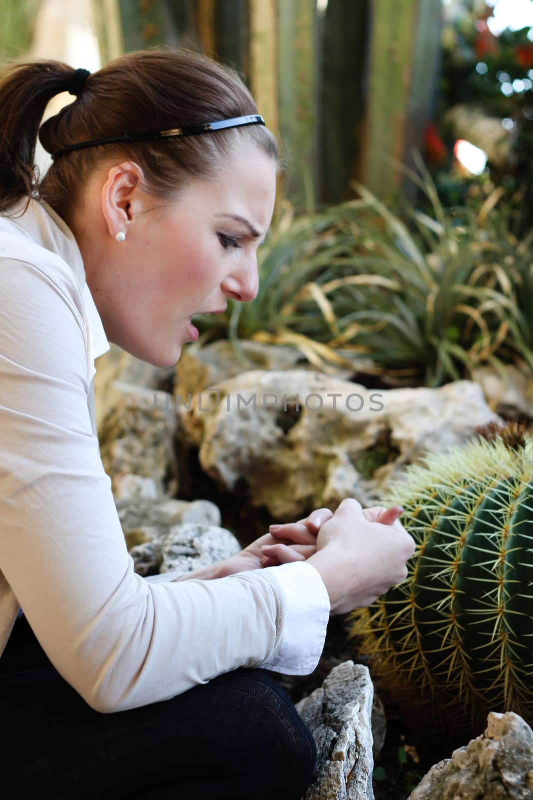 Woman hurt herself on a thorn from a cactus and is holding her hand