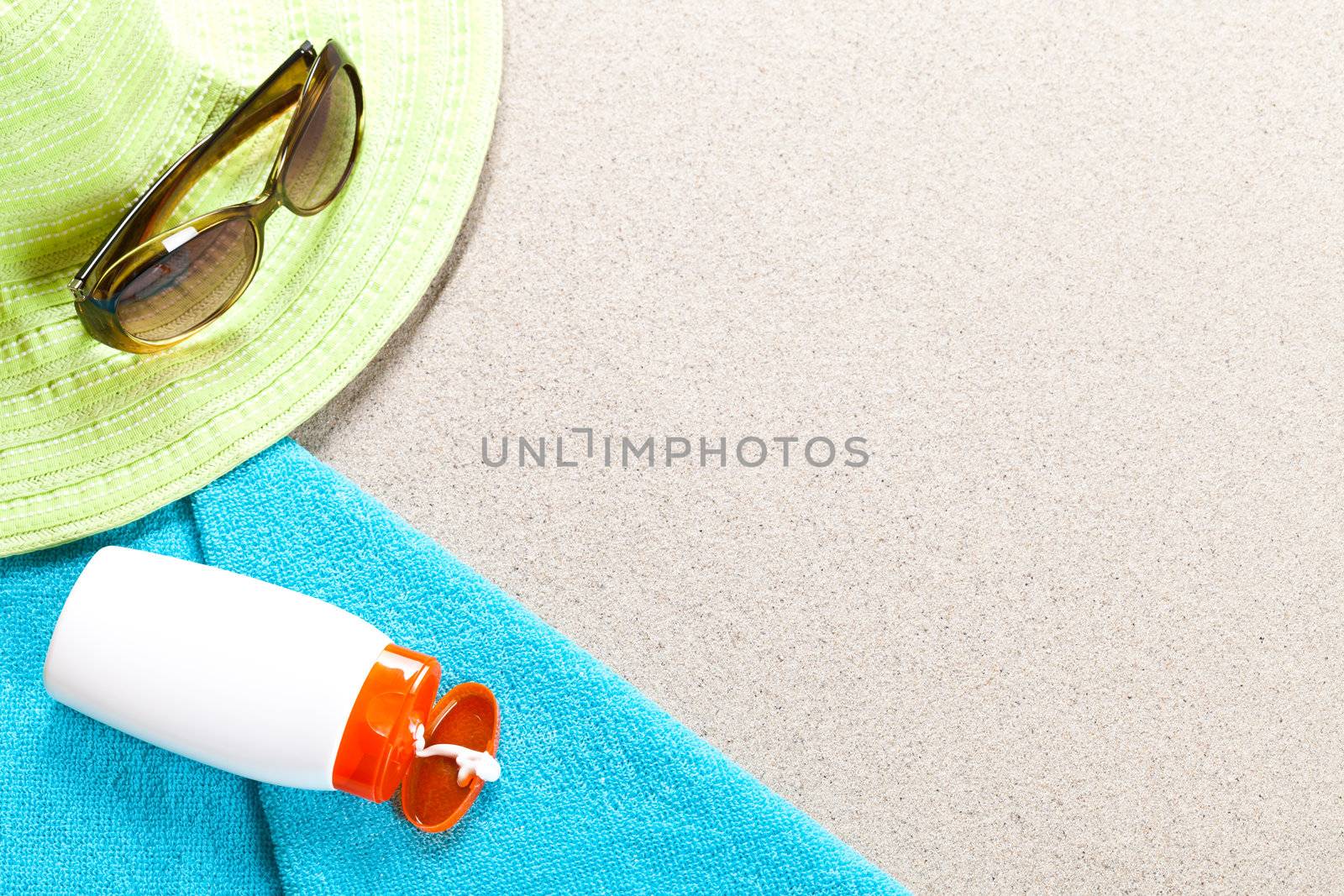 Holidays background. Sunglasses suntan lotion hat and towel on beach. Summer concept with copy space