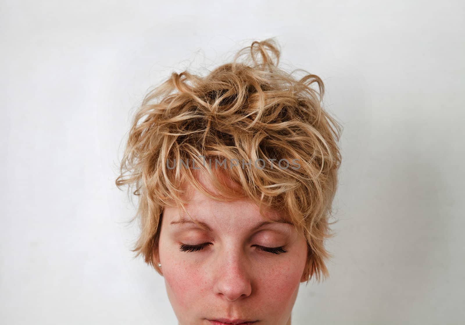 Young blond girl with morning look and mixed hairs on a white background