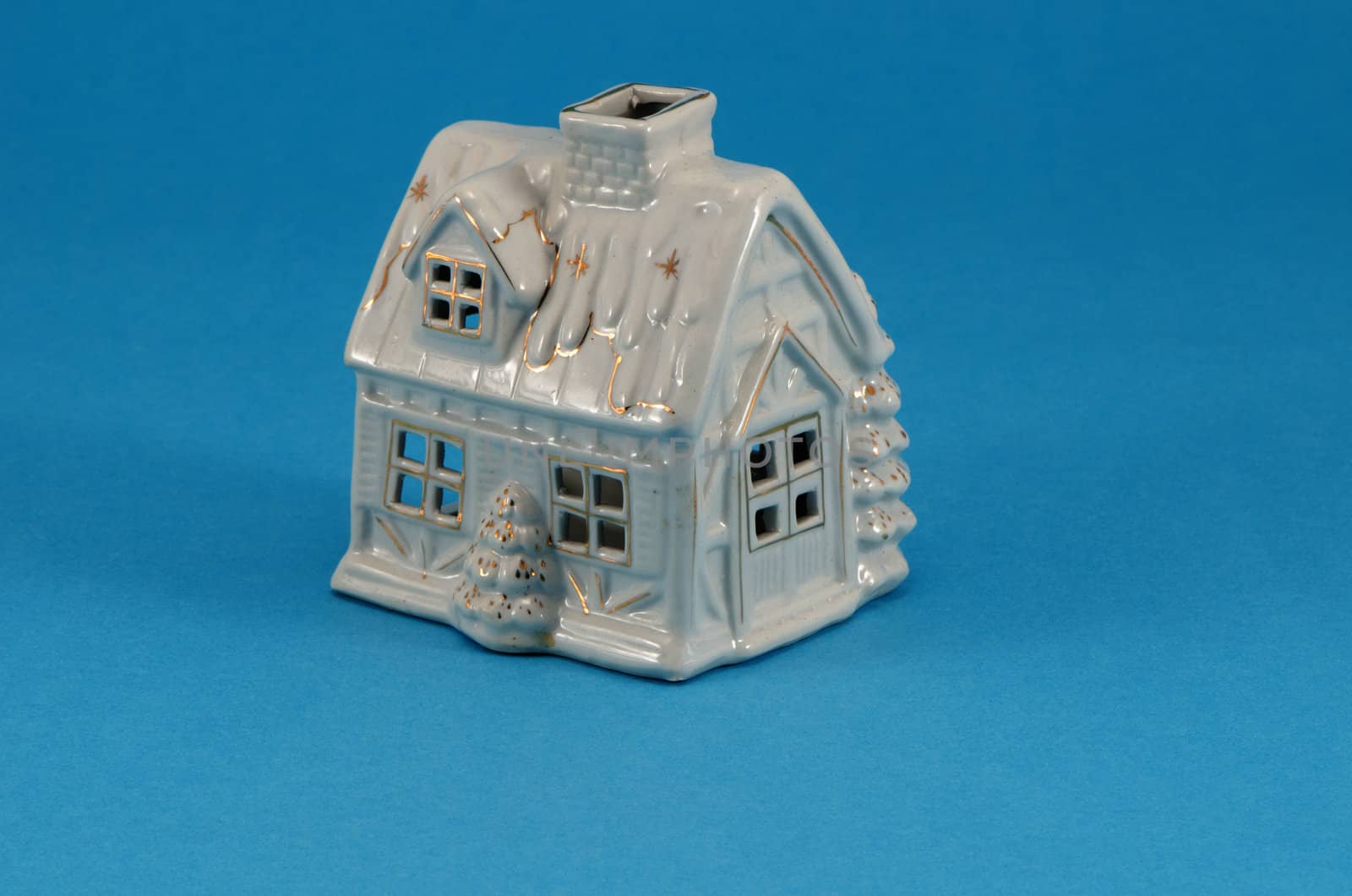 small white ceramic toy christmas house decoration on blue background.
