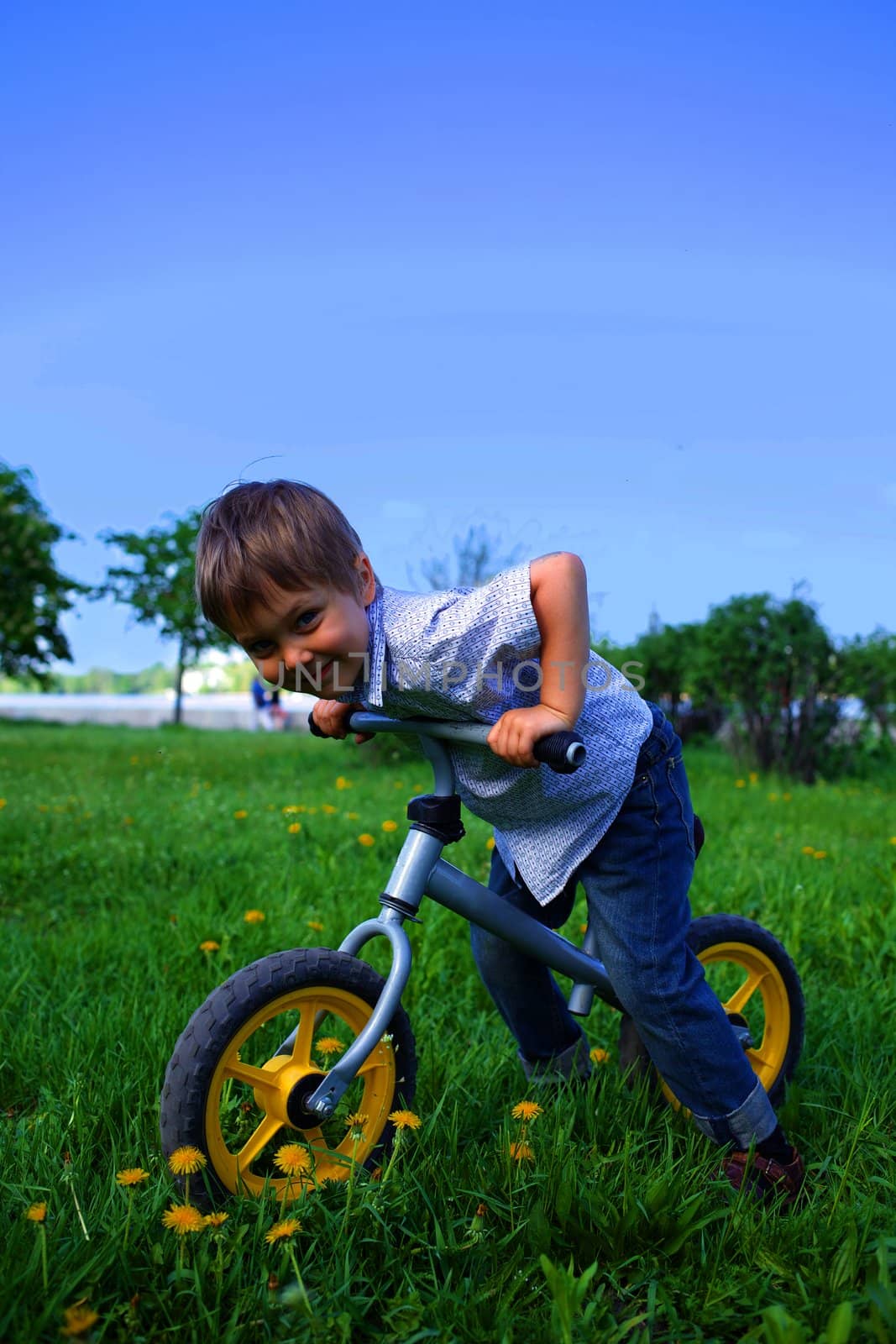 Little boy on a bicycle and his mother in the summer park