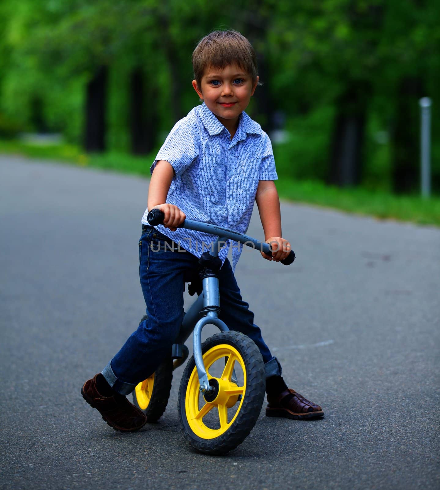 Little boy on a bicycle and his mother in the summer park