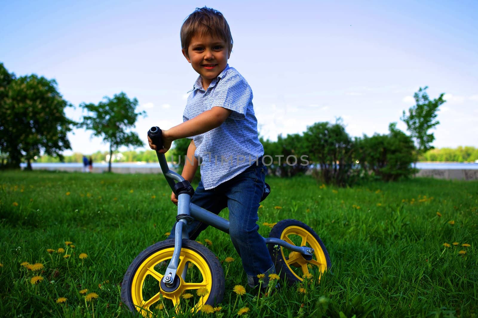 Little boy on a bicycle and his mother in the summer park