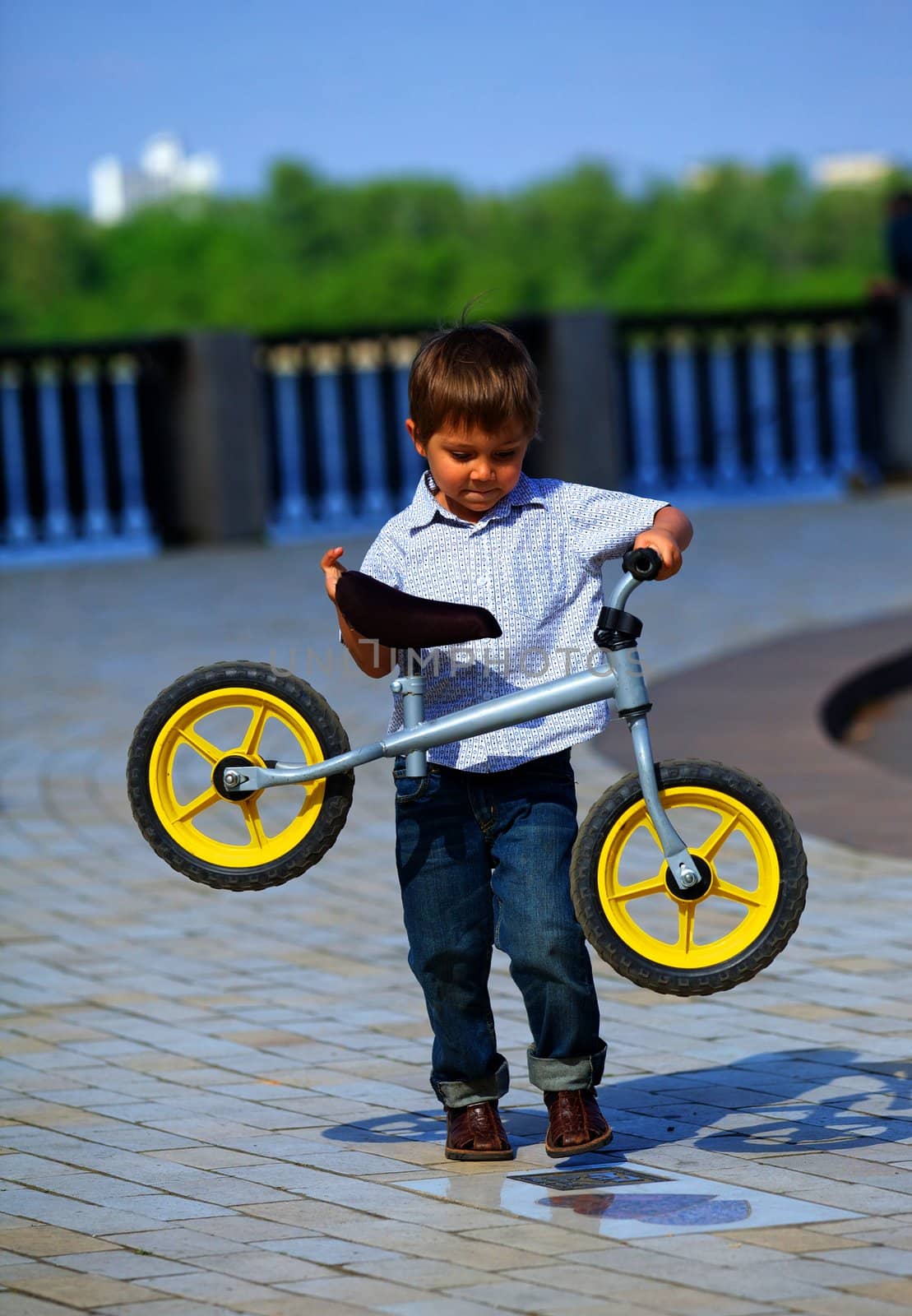 Little boy on a bicycle and his mother in the summer park