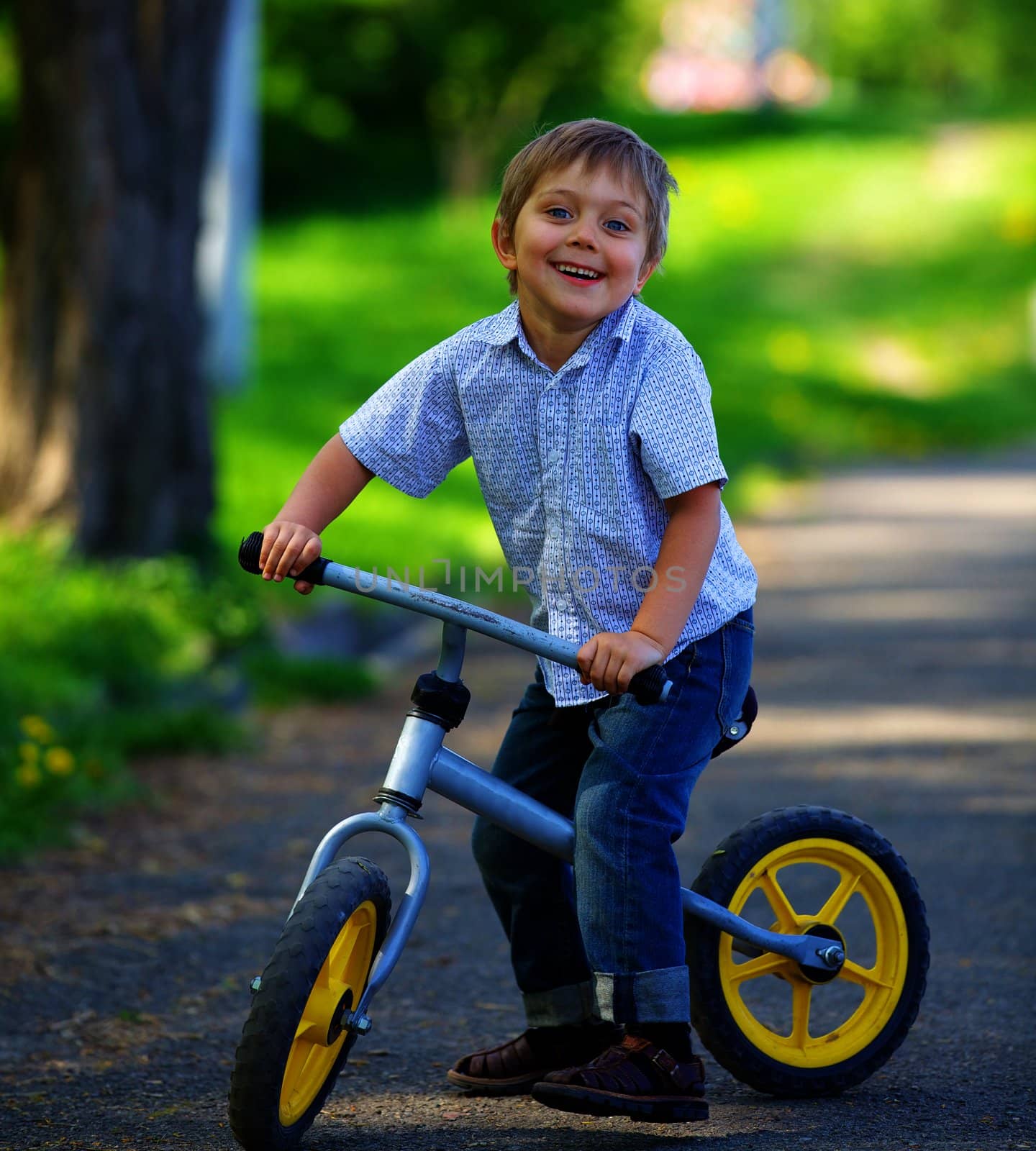 Little boy on a bicycle and his mother in the summer park