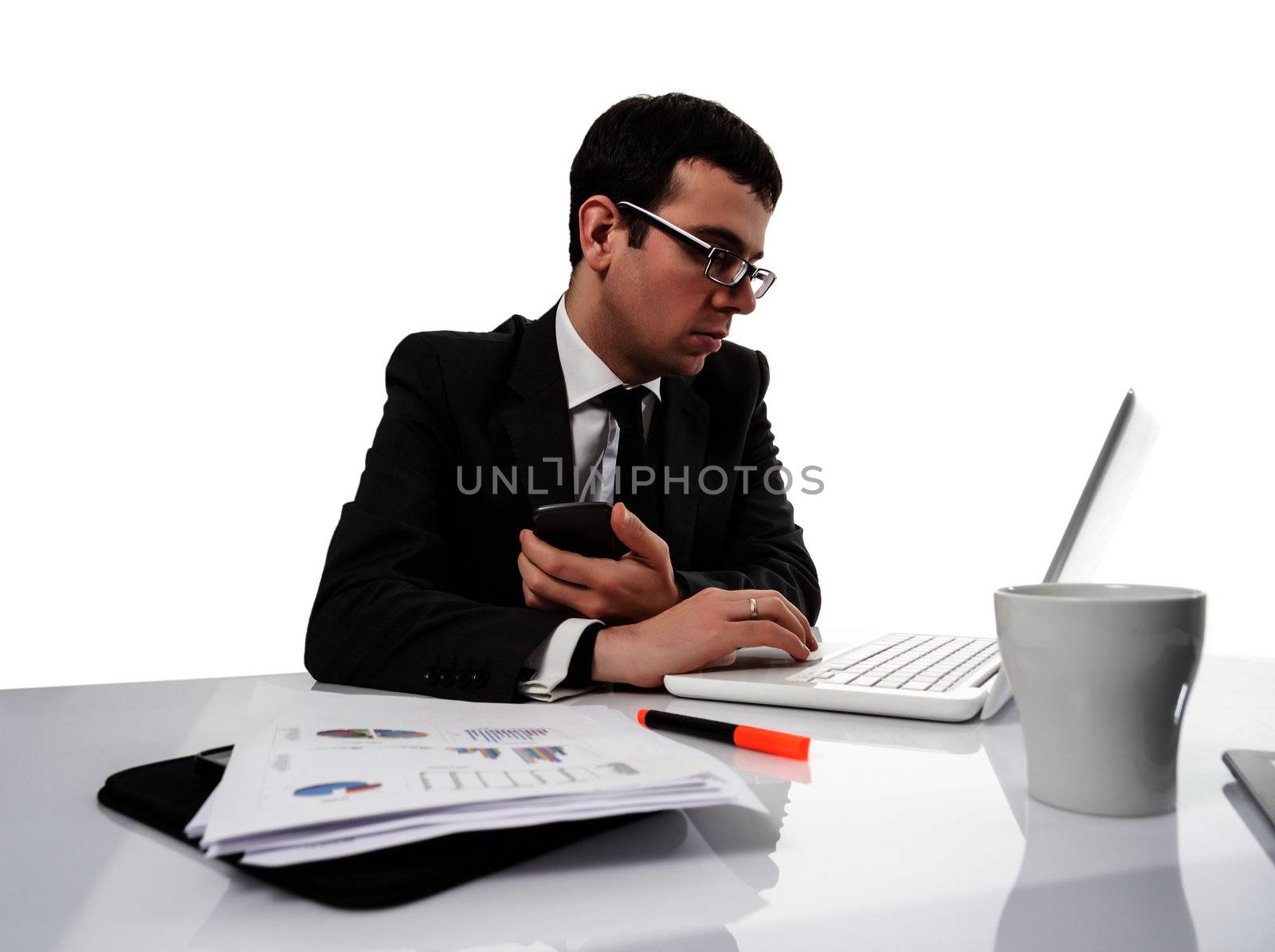 Young executive man working on laptop computer and holding a smartphone in the hand, over a white backgroud