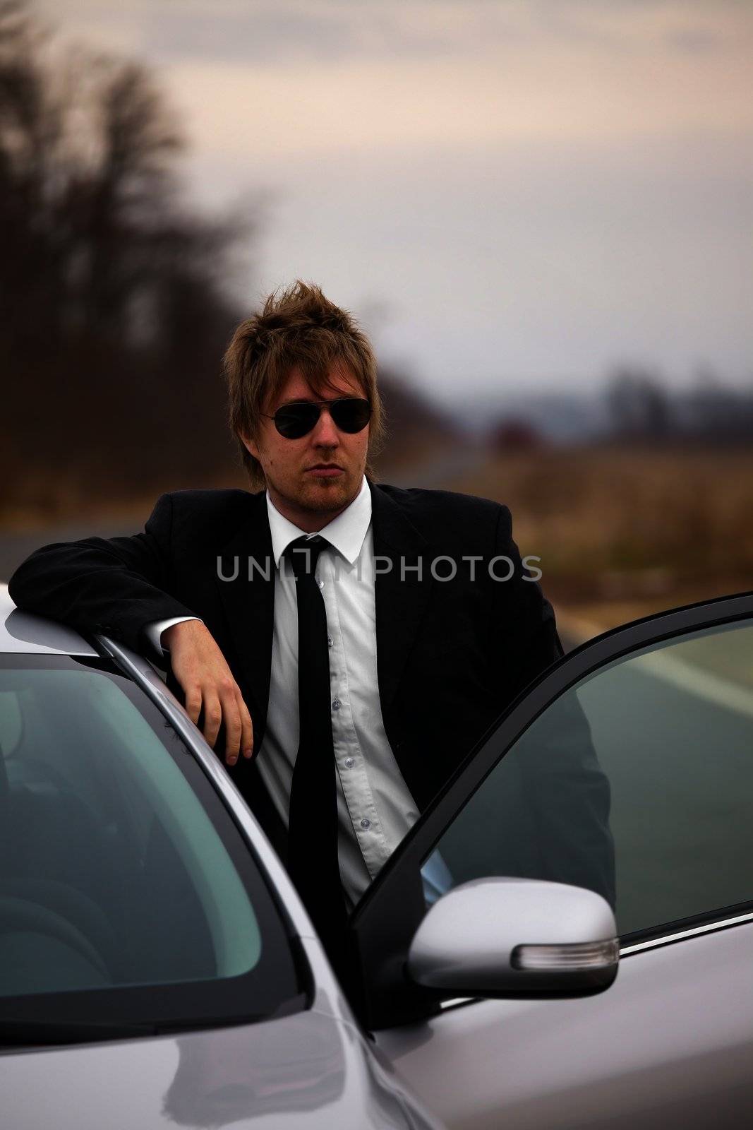 Man in suit standing next to the car