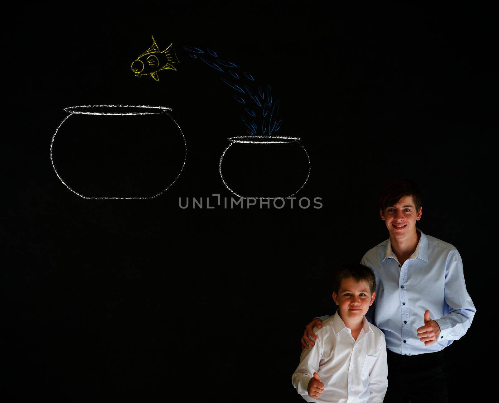 Thumbs up boy dressed up as business man with teacher man and fish jumping from small bowl to big bowl on blackboard background