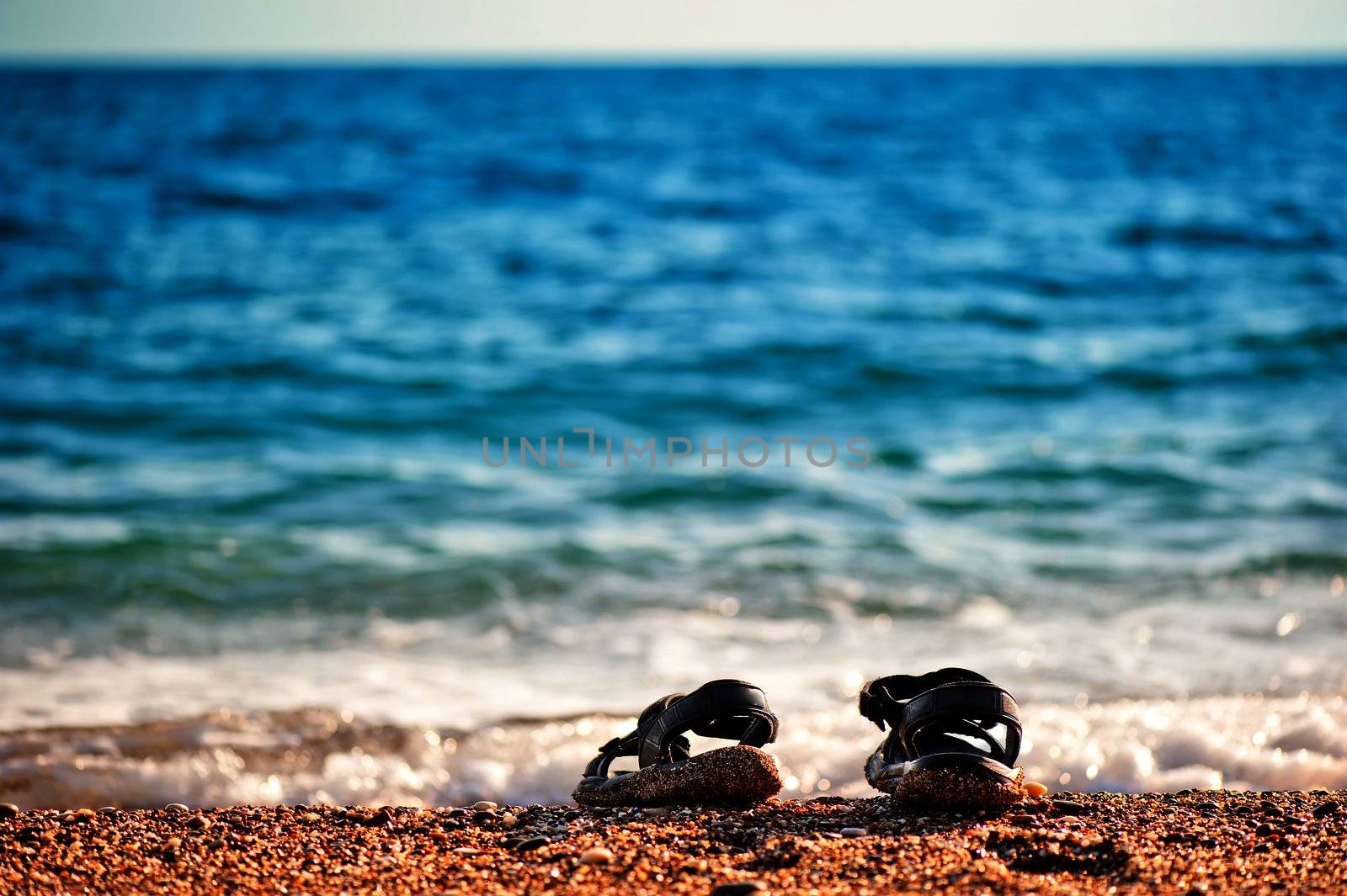 Beach shoes at the edge of the sea on the sandy beach. by kosmsos111