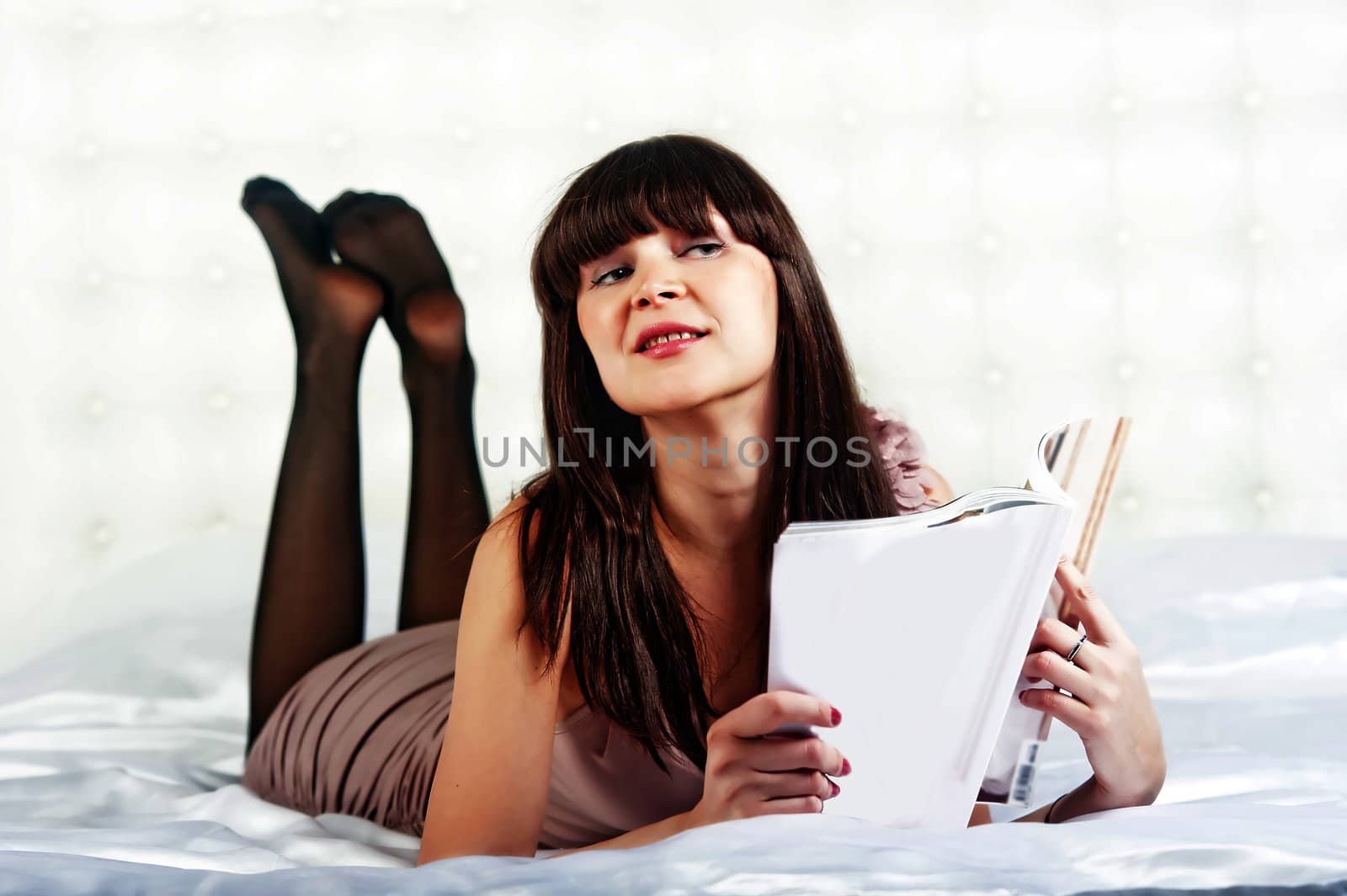 Girl flipping through the magazine while lying on the bed.