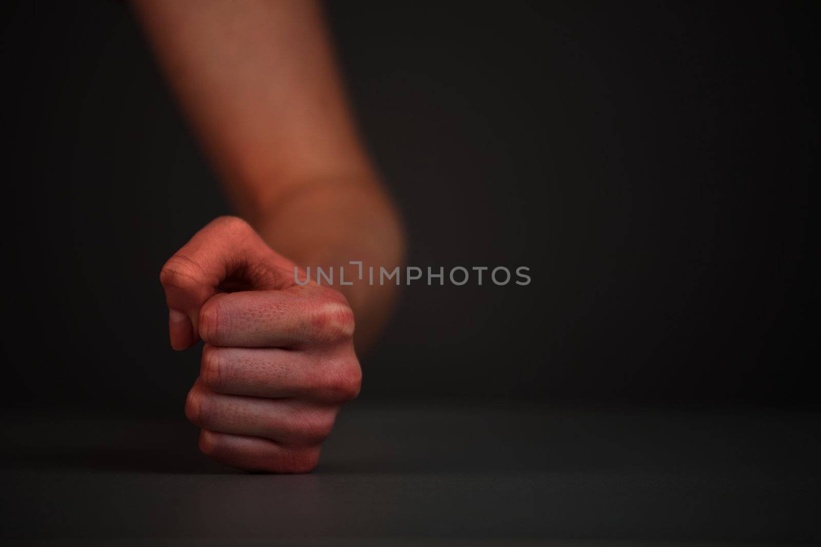 Female fist hits on the table. On gray background