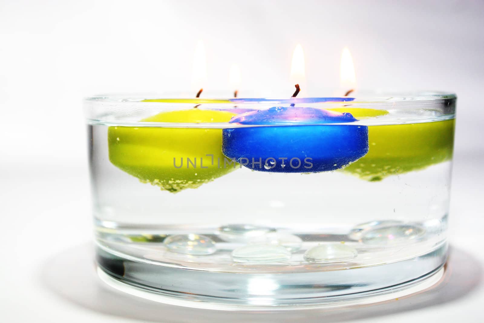 Colored folating candles on water with water drops