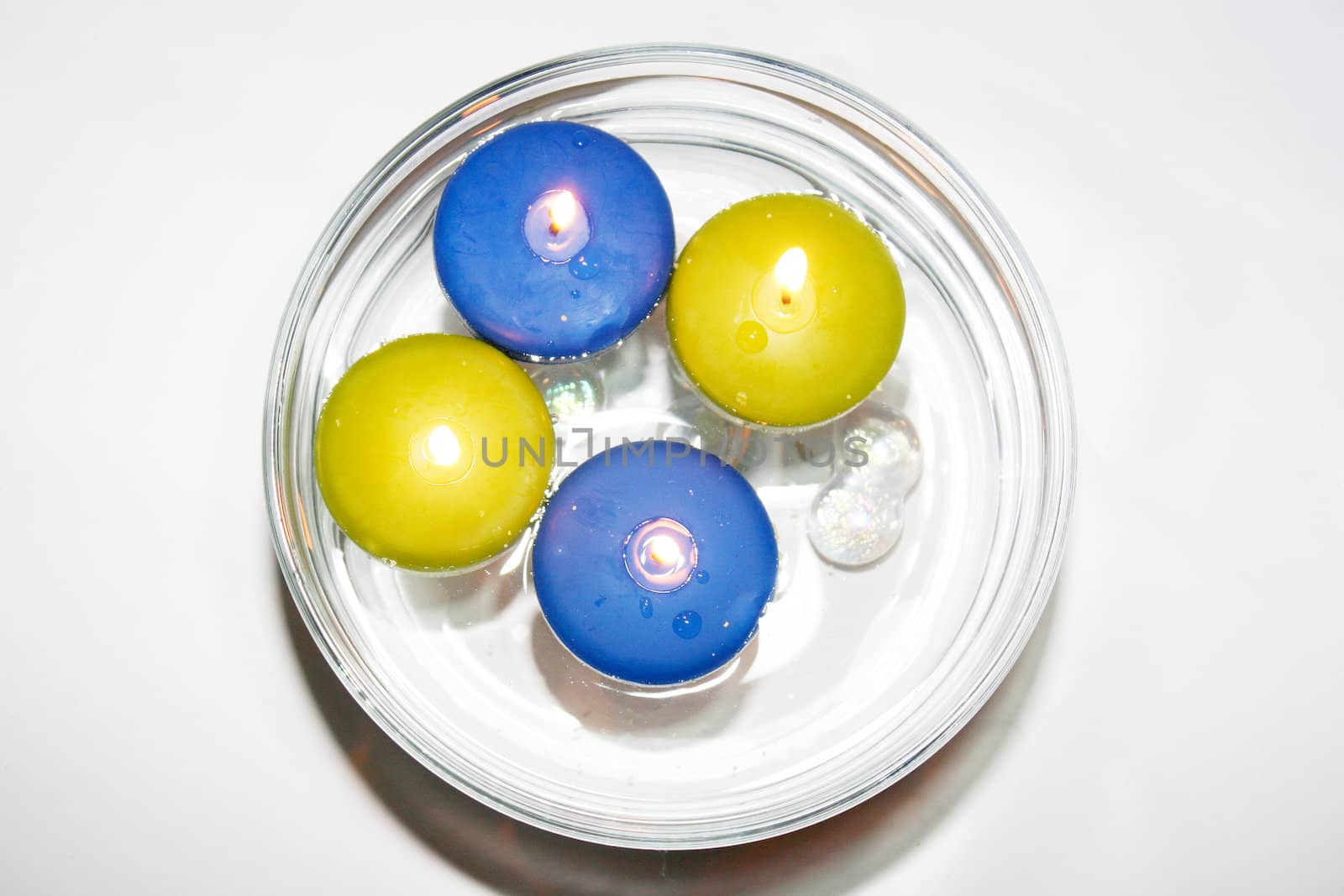 Colored folating candles on water with water drops
