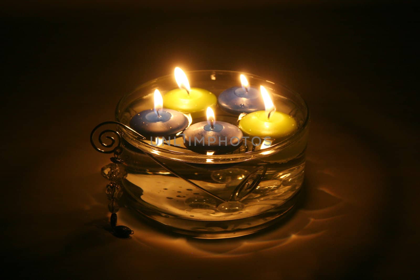 Colored folating candles on water with water drops