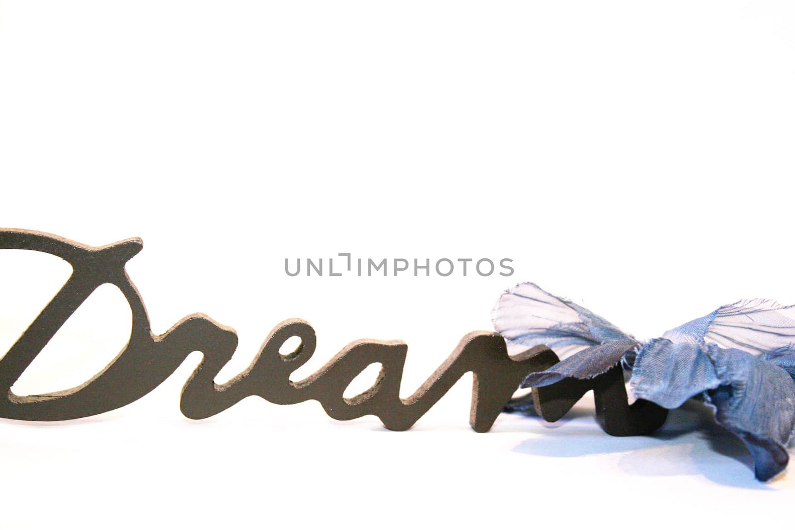 Close-up of the word dream on a white background with a blue bow by valentinacarpin