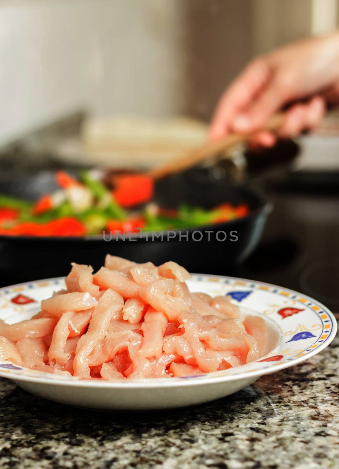 Closeup of raw chiken dish and female cooking in a pan in the ba by doble.d