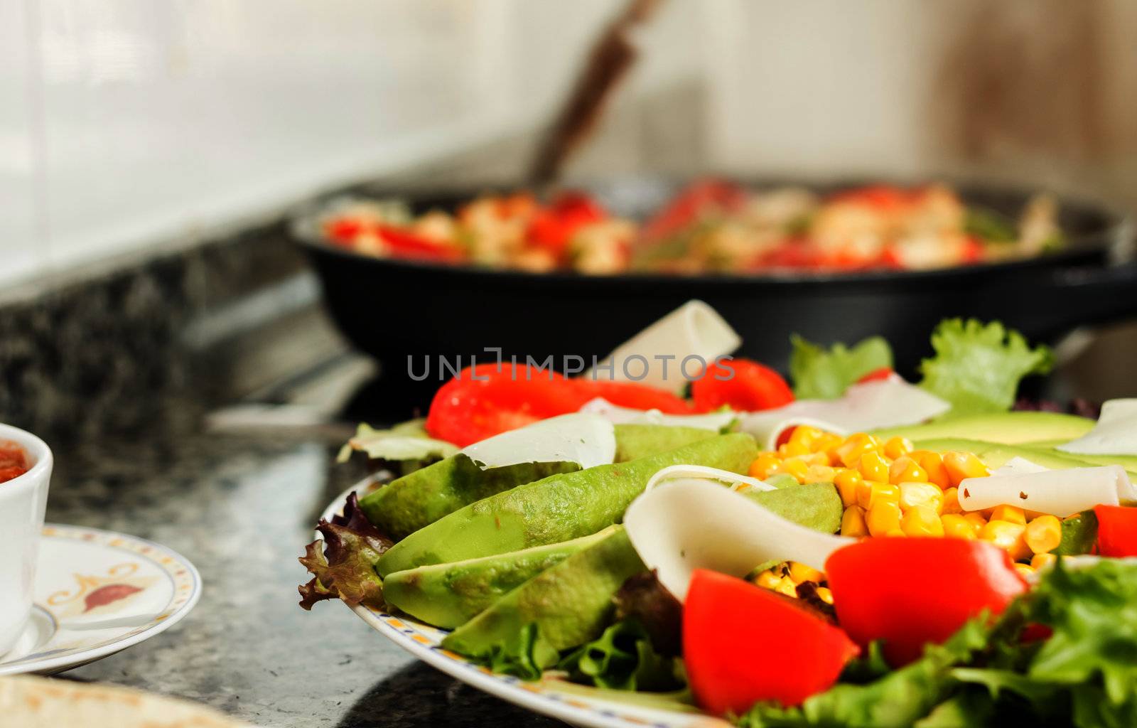 Closeup of fresh salad dish and female cooking in a pan by doble.d