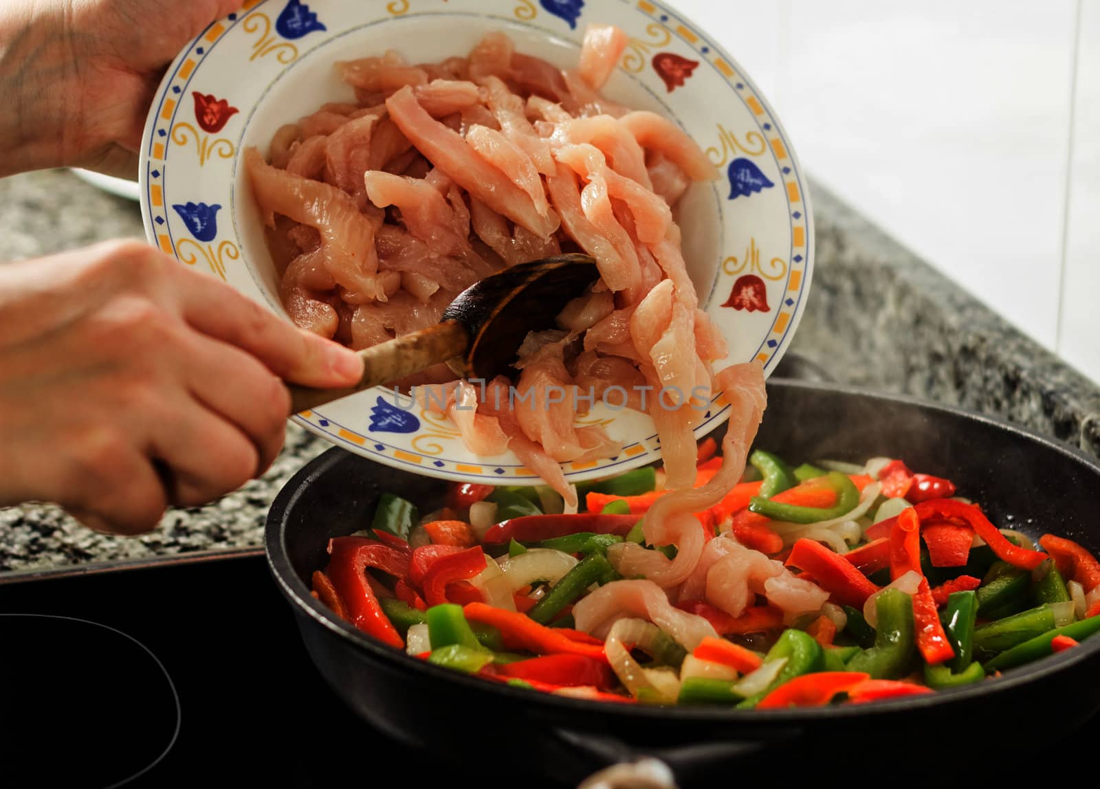 Closeup of female cooking vegetables and chicken in a pan by doble.d