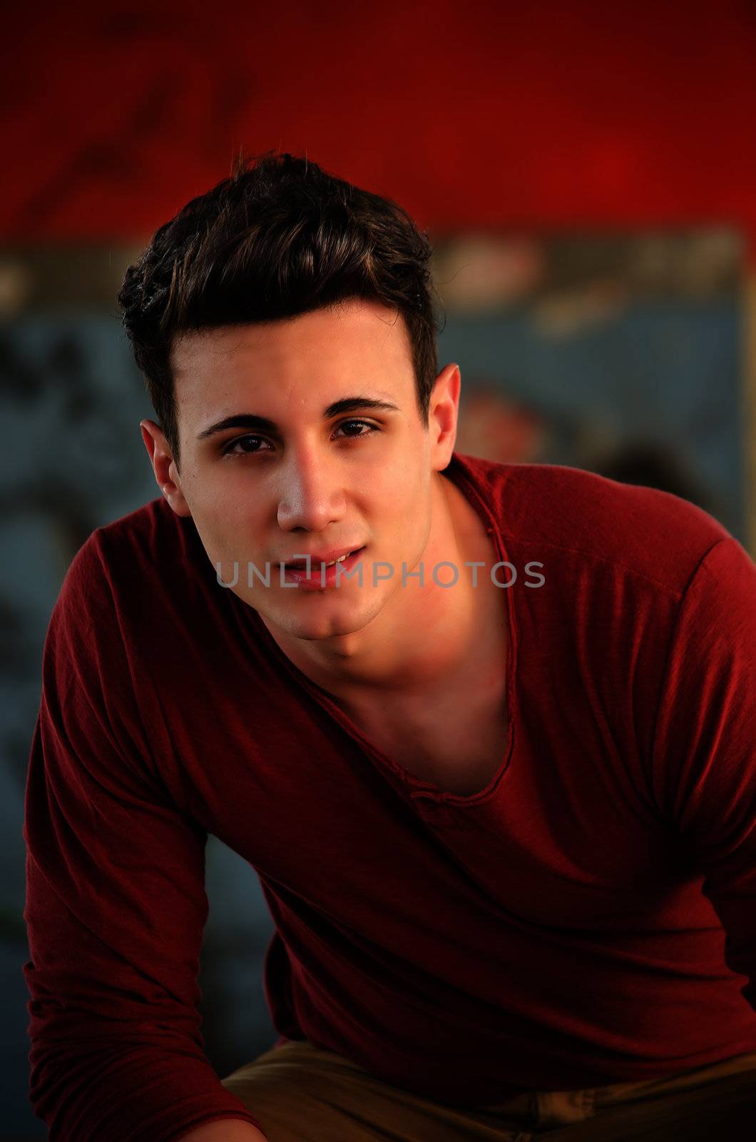 Handsome young man sitting, with red shirt by artofphoto