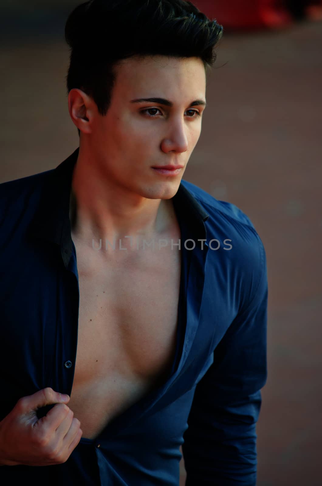 Attractive and trendy young man standing with shirt open showing torso 