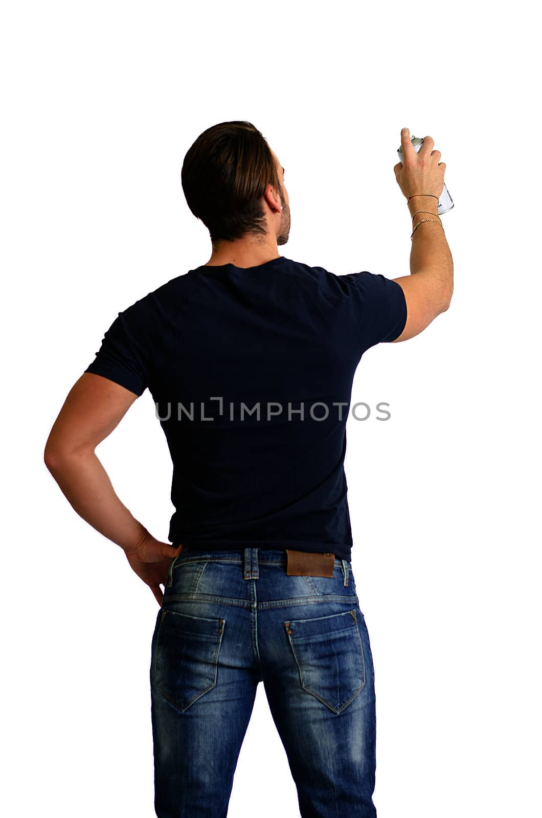 Back of young man with spray paint drawing or writing on empty, blank space seen from behind