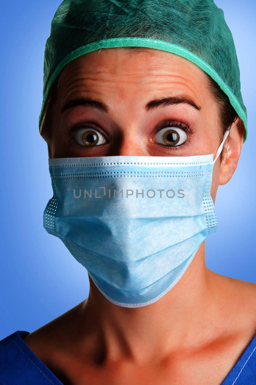 Closeup portrait of a surprised female surgeon, with face mask, in a blue background