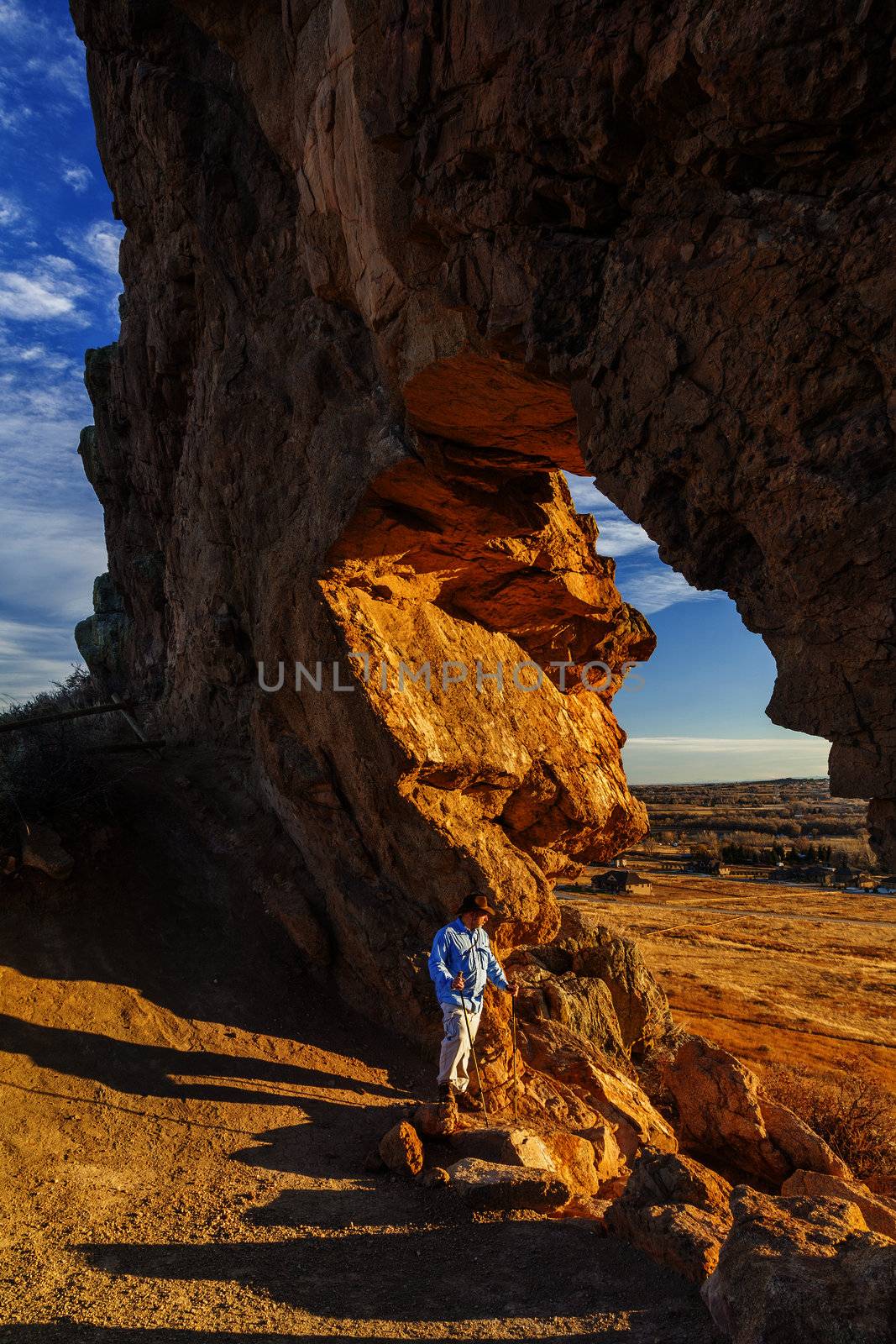 male hiker looking through a keyhole in Devil's Backbone Open Space at foothills of Rocky Mountains near Loveland, Colorado, warm sunset light