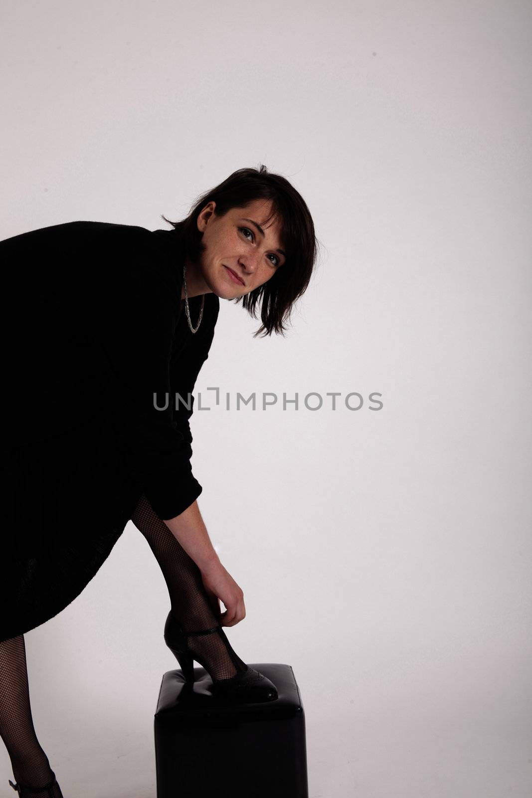 a young woman in strict black dress in studio looking like widow or nanny