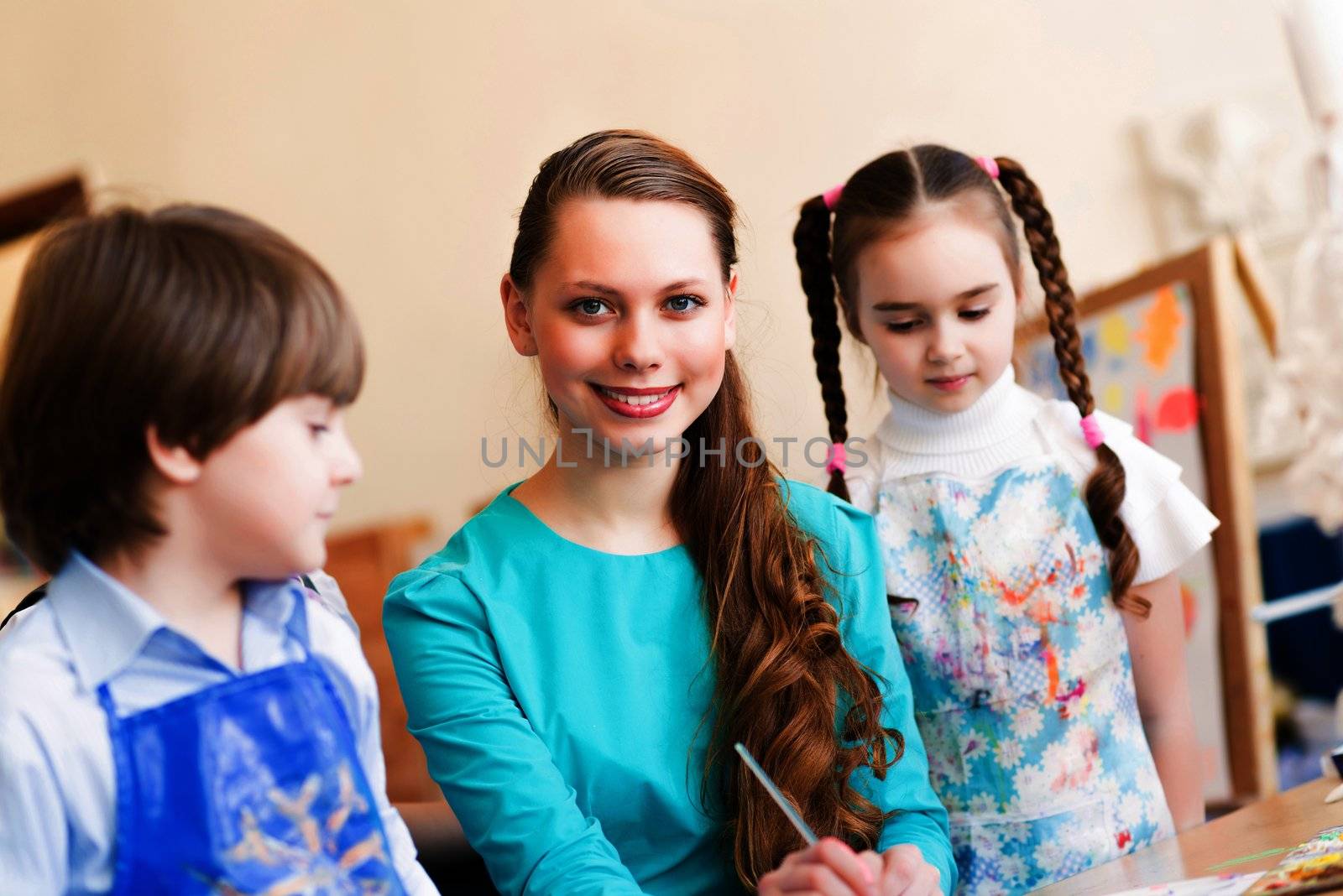 children with the teacher engaged in painting at an art school