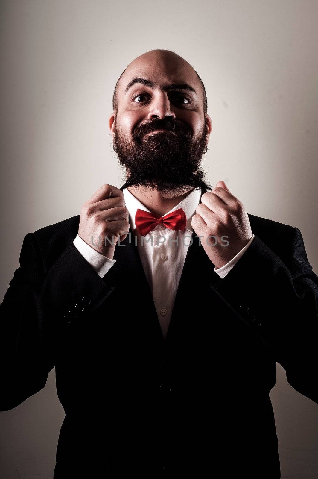  funny elegant bearded man touching beard on vignetting background