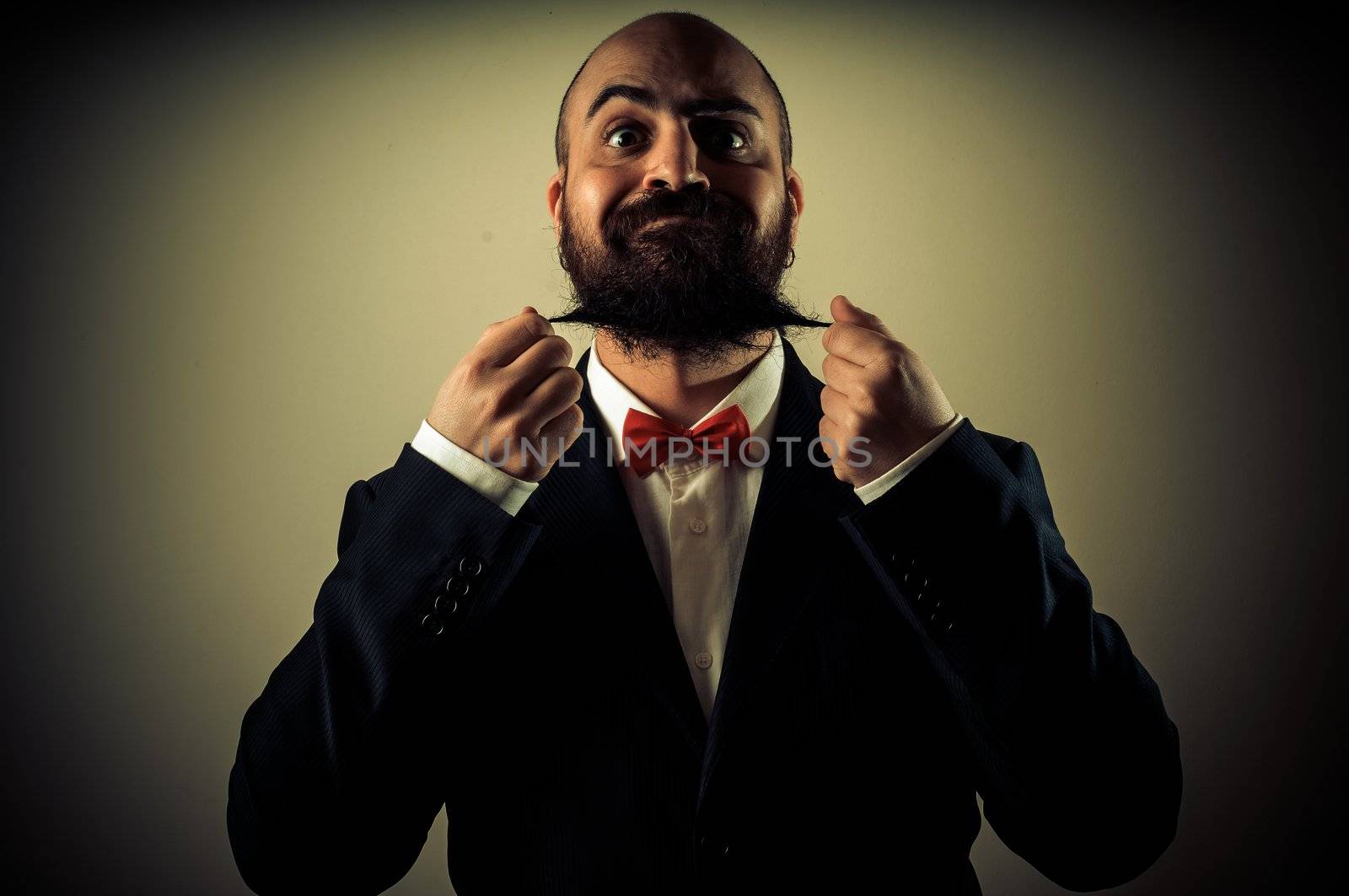  funny elegant bearded man touching beard on vignetting background