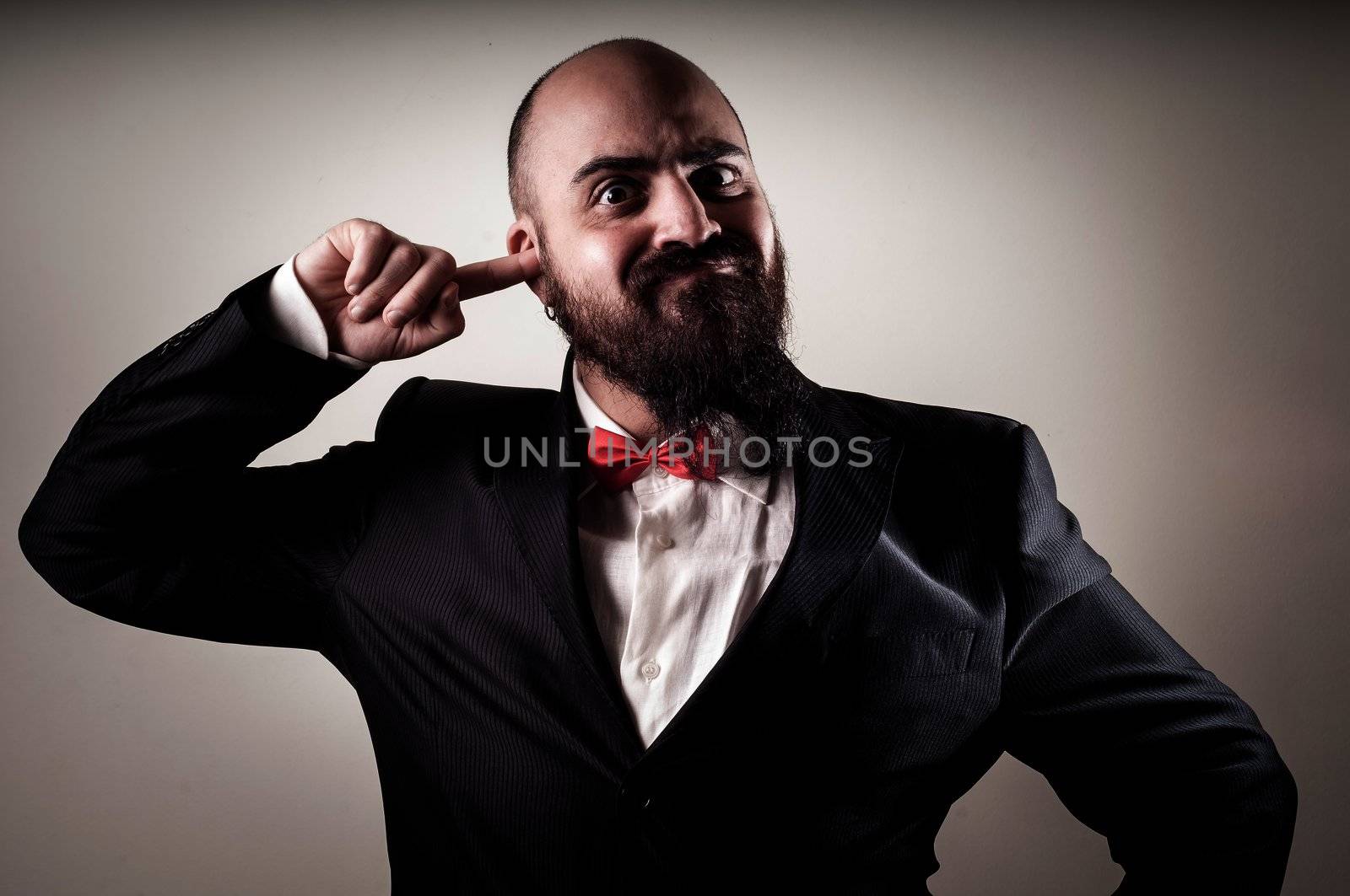  funny elegant bearded man with finger in the ear on vignetting background