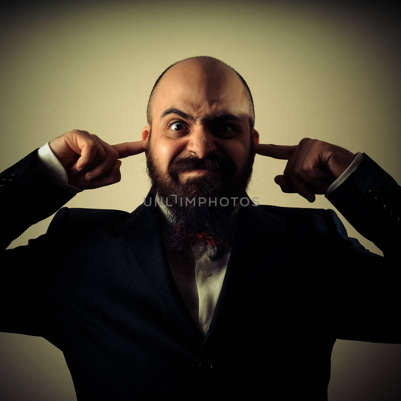  funny elegant bearded man fingers in the ears on vignetting background